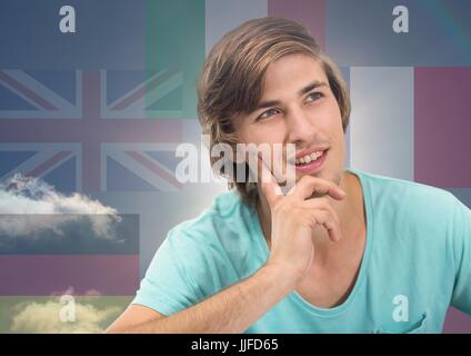 Digital composite of main language flags around young happy man thinking. Sky background Stock Photo