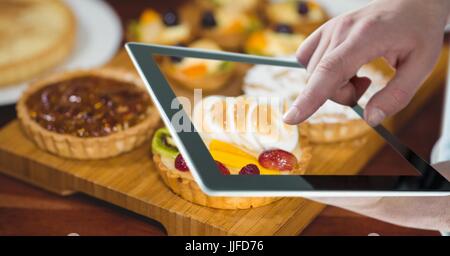 Digital composite of Hand photographing tarts through digital tablet at bakery Stock Photo