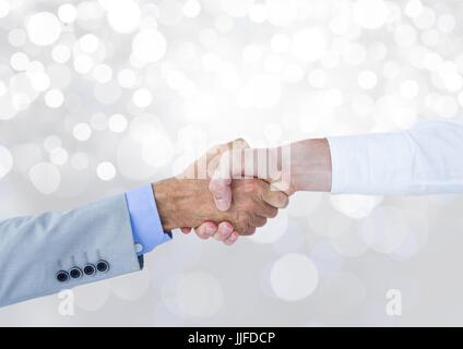 Digital composite of Hands shaking with sparkling light bokeh background Stock Photo
