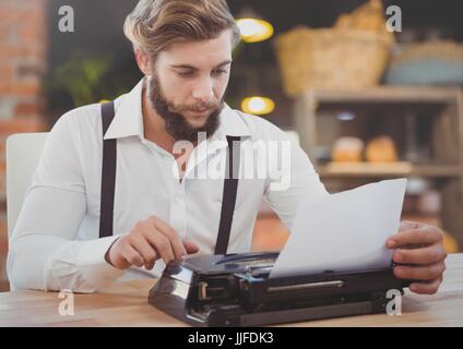 Digital composite of Hipster man  on typewriter in warm cozy room Stock Photo