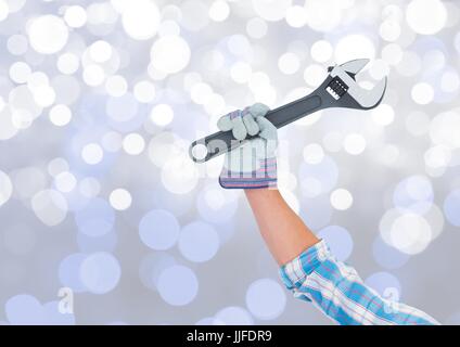 Digital composite of Hand with wrench and sparkling light bokeh background Stock Photo