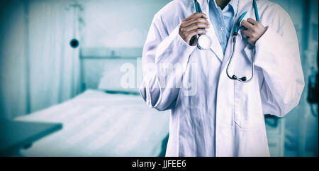 Asian doctor holding stethoscope against bed in clinic Stock Photo