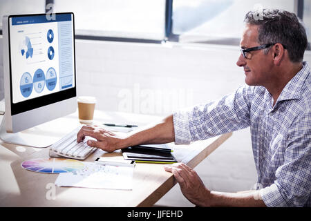 Blue graphics on white background against profile view of a businessman working on computer Stock Photo