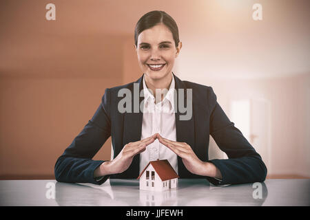 insurer protecting a house by his hands against bright room with wooden floor Stock Photo