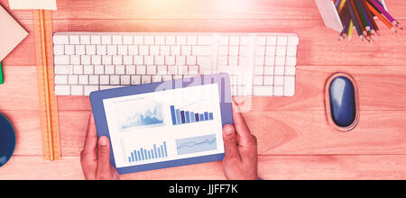 Blue graphics on white background against businessman holding digital tablet while sitting at computer desk Stock Photo