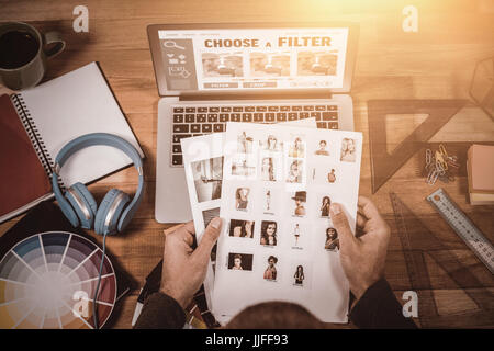 Smartphone app menu against high angle view of photographer selecting photos on desk Stock Photo