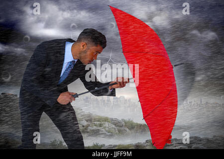 Businessman defending with red umbrella against stormy sky with tornado over cityscape Stock Photo