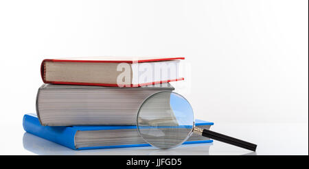 Search concept. Books stack and magnifying glass isolated on white background Stock Photo