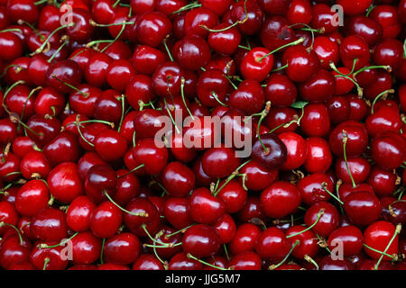 Heap of fresh red ripe sweet black cherry berries on retail market stall display, close up, high angle view Stock Photo