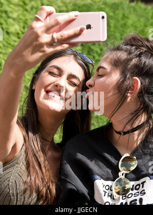 Vertical portrait of two girls taking selfies on their phone. Stock Photo