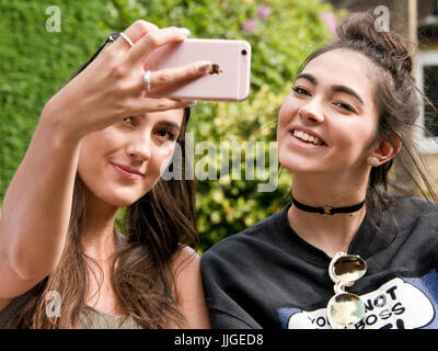 Horizontal portrait of two girls taking selfies on their phone. Stock Photo