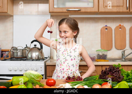 child girl with fruits and vegetables in home kitchen interior, healthy food concept Stock Photo