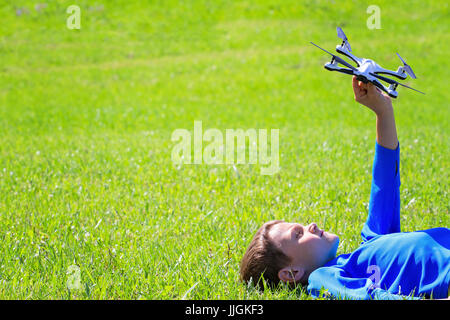 Boy with drone lying on the green grass Stock Photo