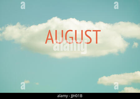 An inscription August written on a beautiful large cloud on a sunny day. Stock Photo