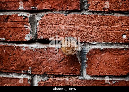 Digital currency physical gold titan bitcoin coin on the brick wall. Stock Photo
