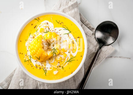 Vegan cuisine. Traditional autumn corn soup. Served with corn cobs, greens, cream. On a white marble table. Copy space top view Stock Photo
