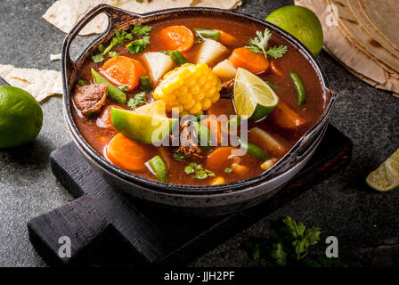 Autumnal vegetable stew. Mexican traditional vegetable soup Mole de olla with meat, potatoes, carrots, beans, corn and lime. Copy space Stock Photo