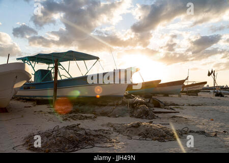 Fishing pangas rest on the beach as the sun sets in Isla Mujeres, Mexico. Stock Photo