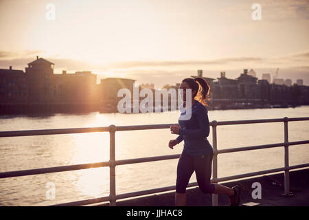 A woman running alongside the River Thames in London. Stock Photo