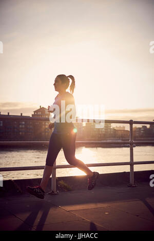A woman running alongside the River Thames in London. Stock Photo