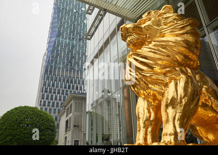 Golden lion as a symbol of power and success in front of a business headquarters skyscraper - Guangzhou CBD, China Stock Photo