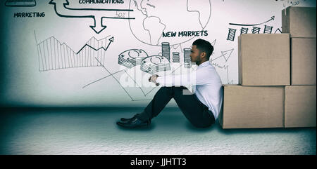 Businessman leaning on cardboard boxes against white background  against grey room Stock Photo