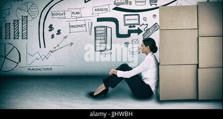Businesswoman leaning on cardboard boxes against white background against grey room Stock Photo