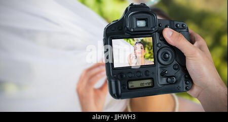 Cropped hand of photographer holding camera  against bride blowing soap bubbles Stock Photo