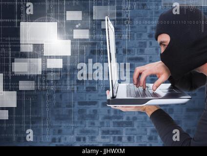 Hacker using a laptop in front of digital background Stock Photo