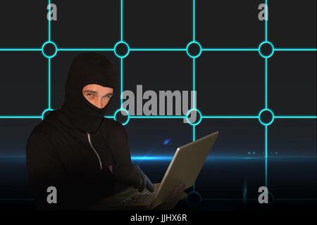 Hacker using a laptop looking at the camera Stock Photo