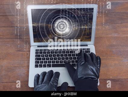Gloved hands typing on a laptop on a wood table Stock Photo