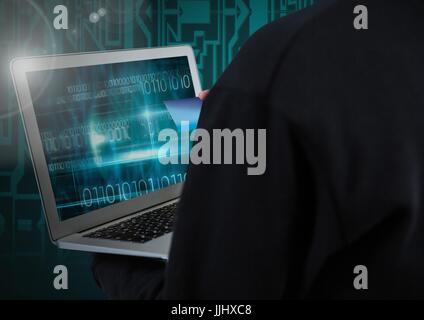 Hacker using a laptop and holding a credit card in front of digital background Stock Photo