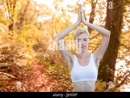 Woman meditating against blurry forest Stock Photo
