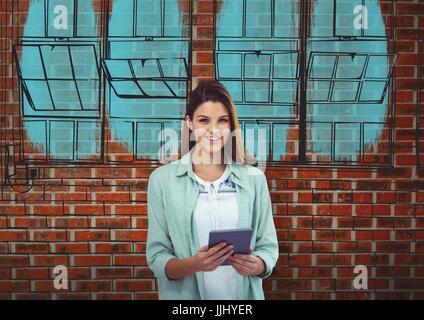 young businesswoman smiling with tablet in front a brick wall with the  blueprint of new building on Stock Photo