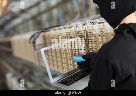 Hacker using a laptop in a data center Stock Photo