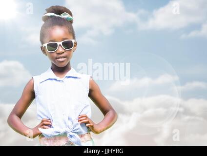 Girl in sunglasses hands on hips against sky with flare Stock Photo