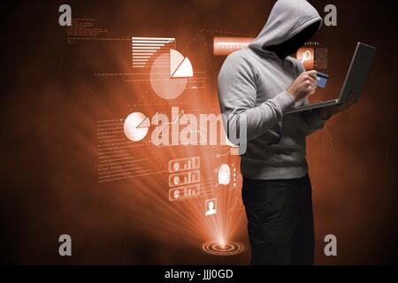 Hacker using a laptop with a debit card on his hands Stock Photo