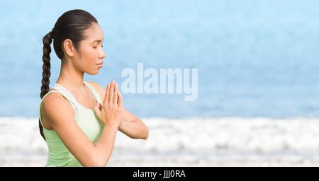 Woman meditating against blurry water Stock Photo