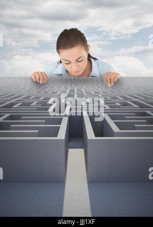 Woman looking down to a 3d maze against blue sky Stock Photo