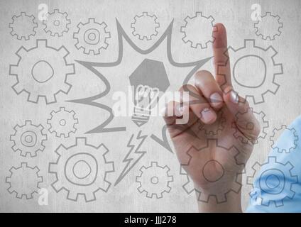 Hand pointing at lightbulb and 3D cog graphics against light grey wall Stock Photo
