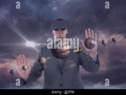 Man in VR headset touching 3D planets against purple sky with clouds and flares Stock Photo
