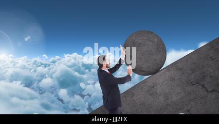 Man pushing rolling round rock Stock Photo