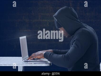 Side view of hacker using a laptop in front of blue background Stock Photo