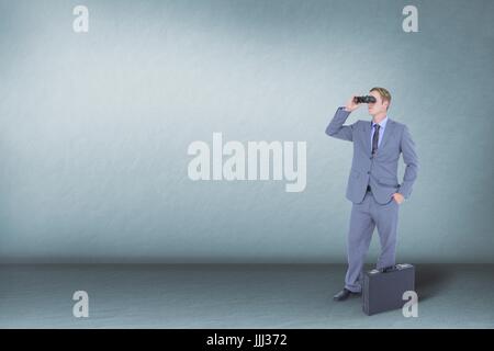 Man looking through binoculars against blue background Stock Photo