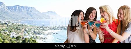 Women with cocktails against blurry coastline Stock Photo