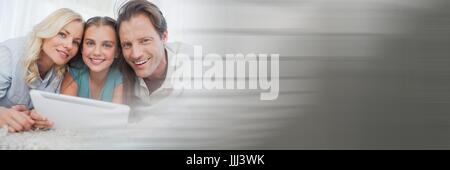 Family on carpet with tablet and blurry grey transition Stock Photo