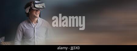Man laughing in virtual reality headset against grey wall and blurry sunset transition and copy spac Stock Photo