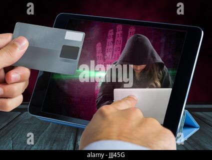 Hands holding a credit card and touching a tablet with a woman hacker on the screen Stock Photo