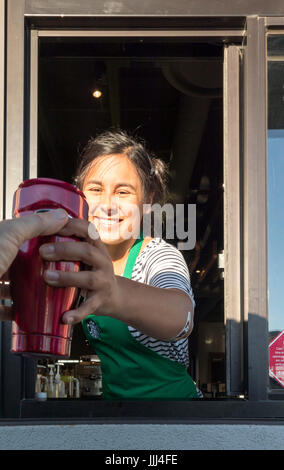 server at Starbucks Drive Thru window taking or receiving coffee travel mug Stock Photo