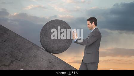 Man pushing rolling round rock Stock Photo